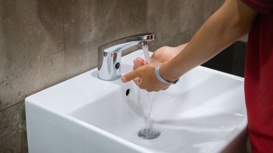 a teenage boy washing his hands at a sink while having OCD