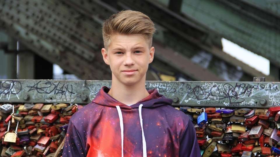 odd in boys hero image of a teen boy standing in front of a wall.