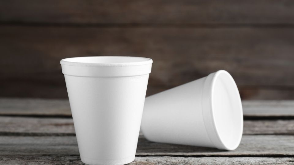 Two Styrofoam cups used for making lean drink sits on a bench